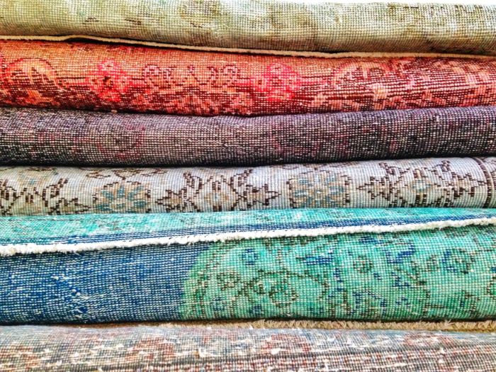 Gestapelte bunte Teppiche mit Mustern, ideal für reinigung und Pflege durch Putzfrau.