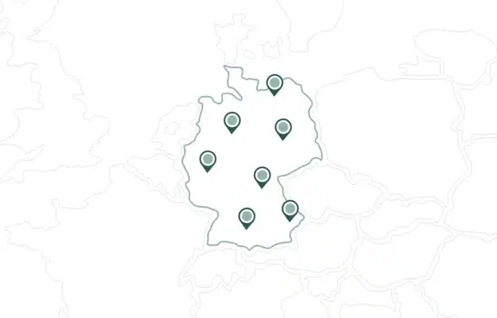 Übersichtskarte Von Deutschland Mit Sieben Stecknadeln, Die Verschiedene Orte Innerhalb Des Landes Markieren; Die Umliegenden Länder Sind Nur Schwach Sichtbar.