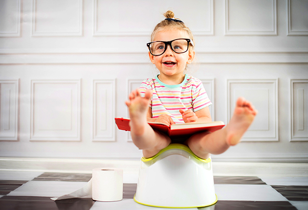 Kind mit Brille liest auf Töpfchen, Toilettenpapier daneben, reinigung erforderlich.