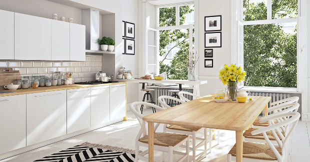 Helle Küche mit Holztisch, weißen Stühlen, gelben Blumen; ideal zum Putzen und Reinigen.