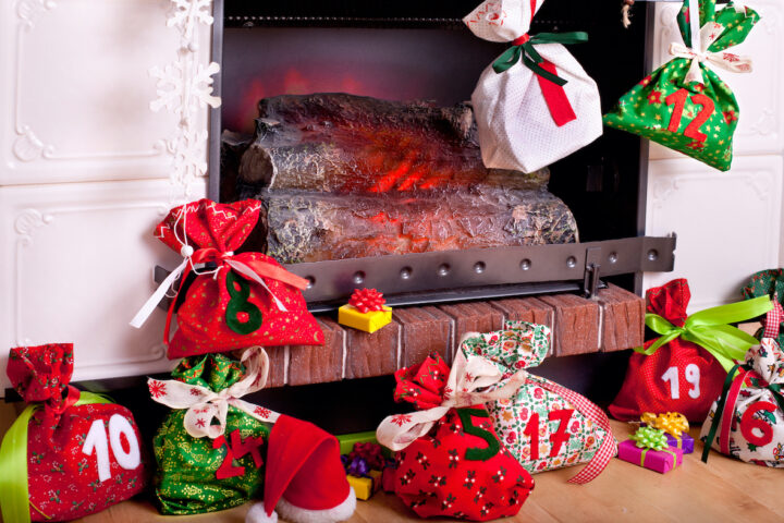 Adventssäckchen vor Kamin dekoriert mit Geschenken, ideal für Putzfrau-Weihnachtsfreude.