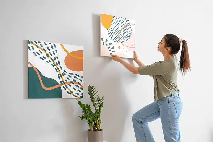 Frau Bringt Bilder An Der Wand An