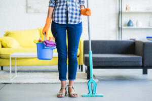 Low Section Young Woman Holding Bucket With Cleaning Supplies Mop