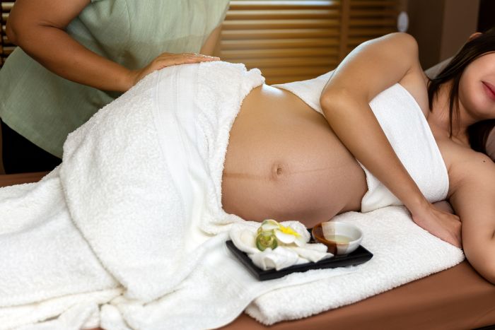 Midsection Woman Massaging Pregnant Customer Lying Bed