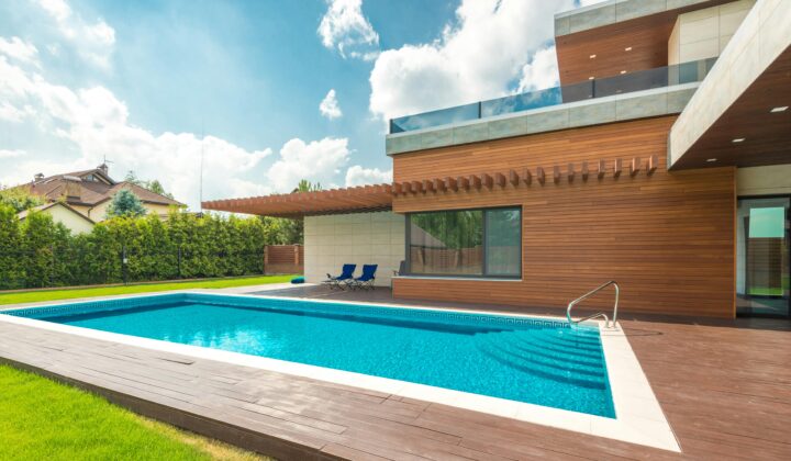 Moderner Pool neben Holzhaus, blauer Himmel, ideal für reinigung und Entspannung.