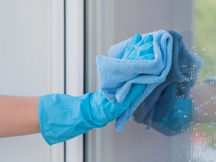Close Up Hand With Rubber Glove Cleaning Window