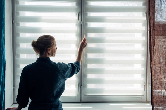 Young Woman Gown Stands Near Window With Blinds
