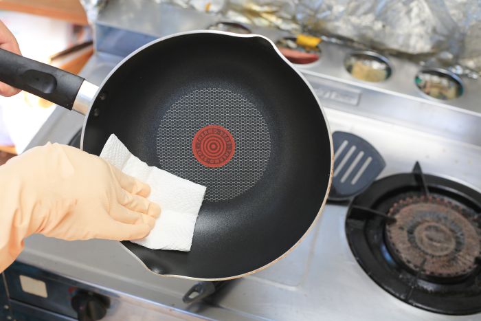 Cropped Hands Cleaning Cooking Pan Against Stove Kitchen
