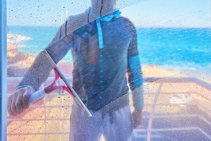 Man Is Cleaning Dirty Glass Window With Wiper Brush Inside View
