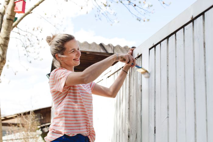 Smiling Woman Painting Fence Yard