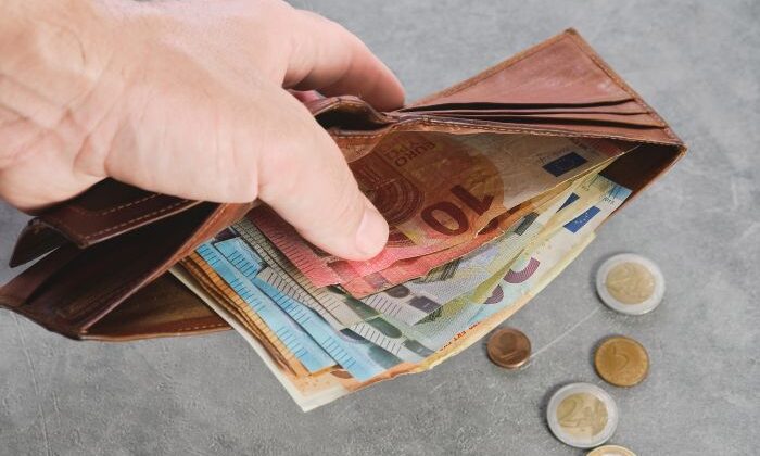 Hand Hält Portemonnaie Mit EuroScheinen, Münzen Auf Grauem Tisch, Thema: Reinigungskraft.