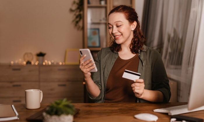 Frau Am Schreibtisch Mit Smartphone Und Kreditkarte, Lächelnd. Thema: OnlineShopping.