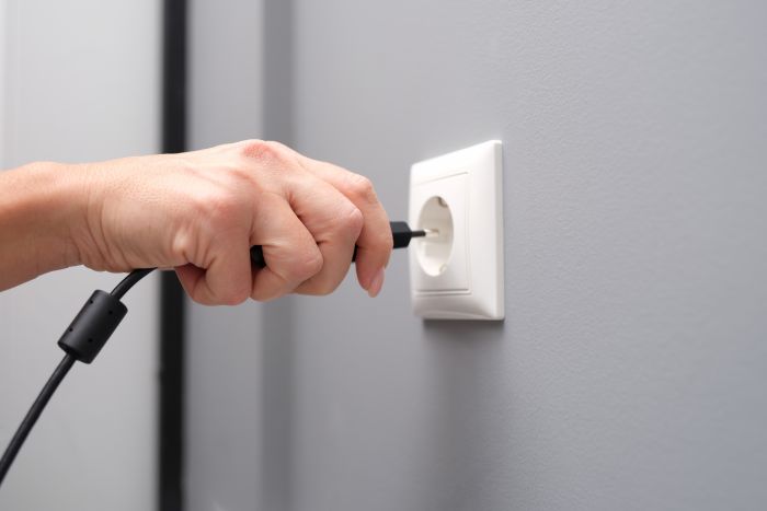 Woman Hand Inserts Electrical Plug Into Outlet Closeup