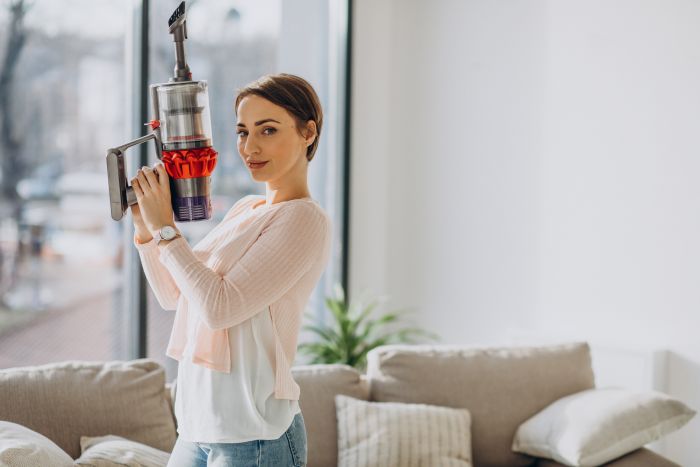 Young Woman With Rechargeable Vacuum Cleaner Cleaning Home