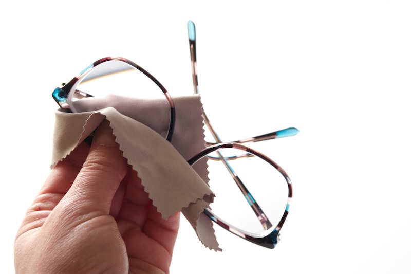 Bunte Brillen Von Hand Mit Einem Weichen Mikrofasertuch Reinigen. Nahaufnahme, Isoliert Auf Weißem Hintergrund, Vermittelt Sorgfalt Und Liebe Zum Detail.