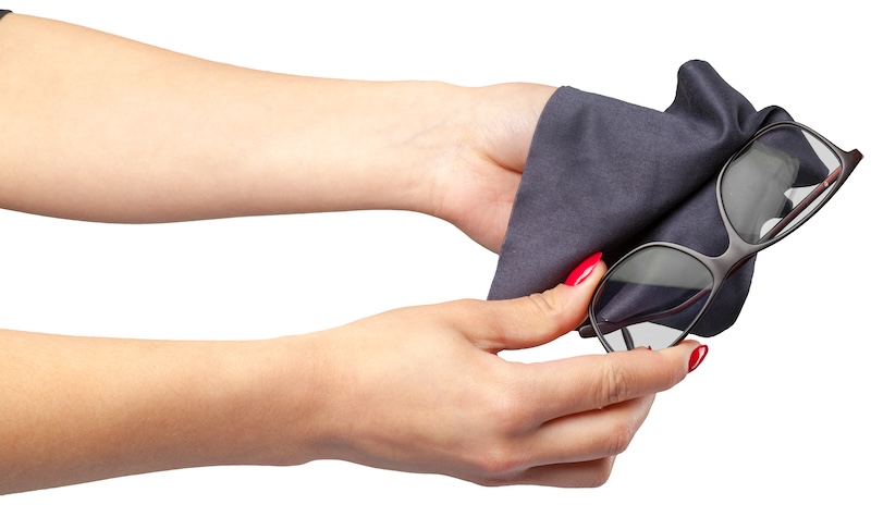 Hände Halten Ein Schwarzes Mikrofasertuch Und Reinigen Sonnenbrillen Mit Manikürten Nägeln Mit Roter Spitze. Der Ton Ist Ordentlich Und Auf Sorgfalt Ausgerichtet.