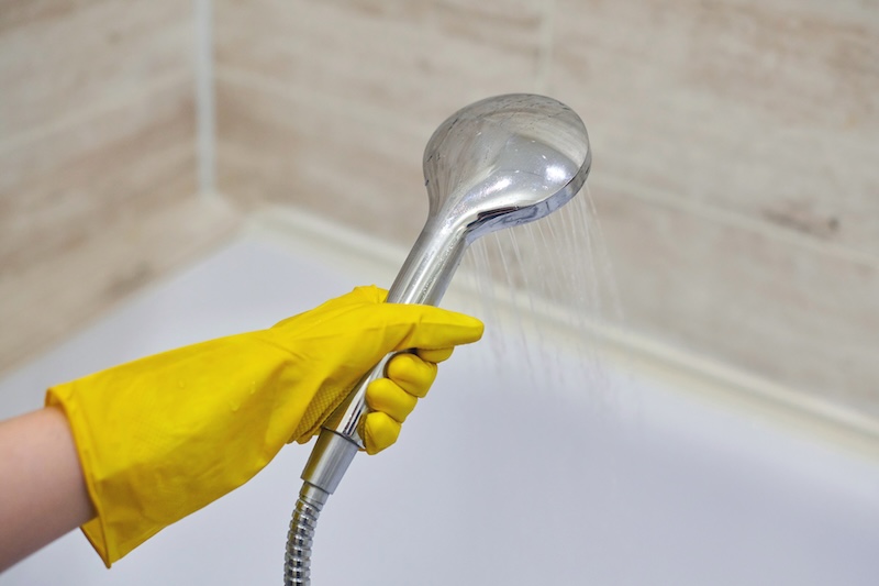 Female Hand Protective Yellow Rubber Glove Holding Shower Head With Pouring Water Domestic Bathroom