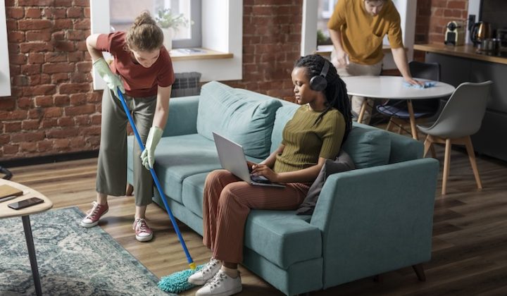 people sitting in a living room with one of them cleaning the floor