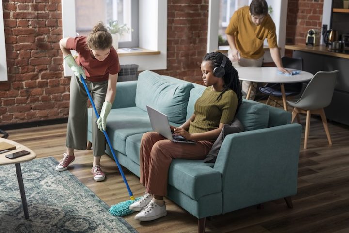 people sitting in a living room with one of them cleaning the floor