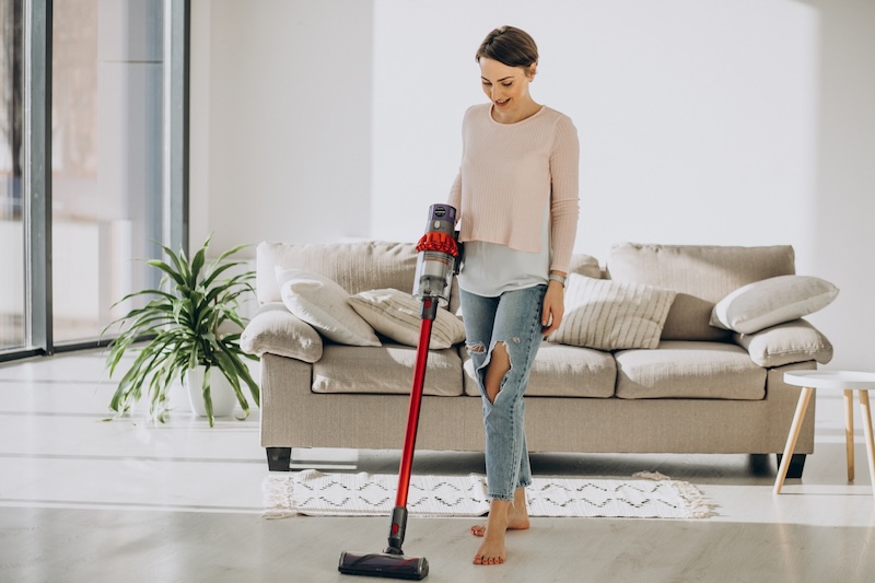 Young Woman With Rechargeable Vacuum Cleaner Cleaning Home